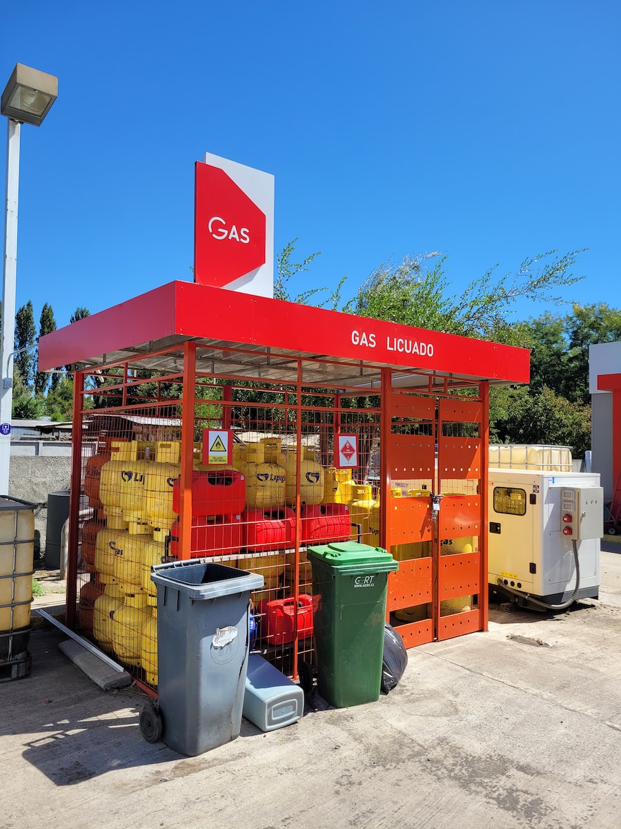 a gas station with a red canopy and yellow containers